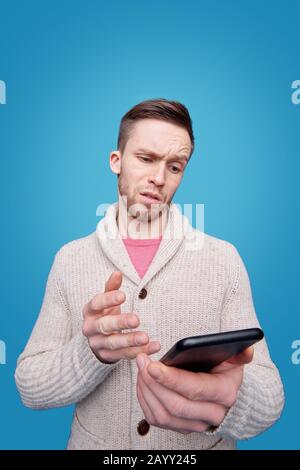 Portrait d'un jeune homme barbu sérieux aux yeux bleus sur fond bleu vif Banque D'Images