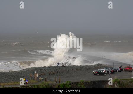 Le temps de tempête crée de grandes vagues qui frappent dans Aberystwyth, au Pays de Galles, tandis que les spectateurs sont éclipis par la taille des vagues. Banque D'Images