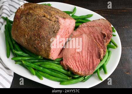 Bœuf rôti moyen Rare avec haricots verts : filet de bœuf rôti moyen sur un plateau de haricots verts Banque D'Images