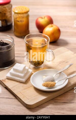 Différents types de sucre se trouvent sur une planche en bois. Thé préparé dans un verre. Banque D'Images