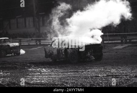 Années 1970, historique, une voiture de course banger avec de la fumée qui coule d'un moteur battue, Angleterre, Royaume-Uni. Dans les courses de banners, de vieilles voitures de ferraille sont utilisées et le contact avec les voitures de crash et les dommages des voitures d'opposants est autorisé, ce qui entraîne une collision de voitures coincées sur le circuit. Banque D'Images