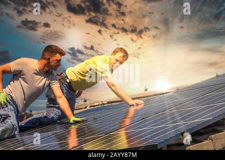 Portrait des travailleurs qui installent des panneaux photovoltaïques sur le toit Banque D'Images