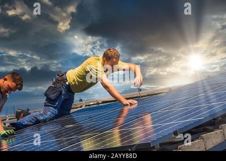 Portrait des travailleurs qui installent des panneaux photovoltaïques sur le toit Banque D'Images