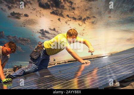 Portrait des travailleurs qui installent des panneaux photovoltaïques sur le toit Banque D'Images