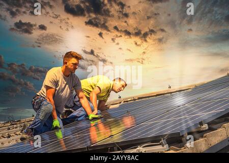 Portrait des travailleurs qui installent des panneaux photovoltaïques sur le toit Banque D'Images