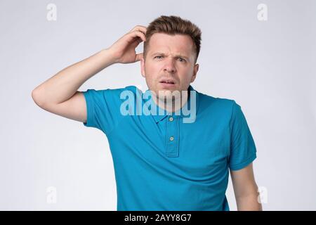 Beau jeune homme caucasien souriant avec une expression de pensée, isolé sur un fond blanc Banque D'Images