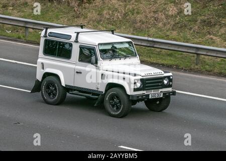 S100DEF Land Rover Defender 90 County Sw Swb véhicule diesel blanc se déplace sur l'autoroute   près de Preston dans Lancashire Banque D'Images