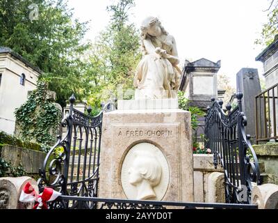 Tombe de Frédéric Chopin en pierre blanche avec une statue d'une jeune dame en deuil et buste du pianiste derrière une clôture noire avec ruban polonais Banque D'Images