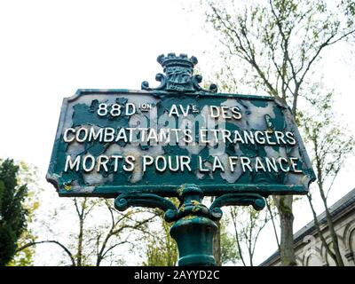 Ancien signal vert avec le nom des boulevards écrits en français avec un fond d'arbres et de monuments funéraires dans un cimetière monumental Banque D'Images