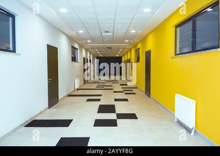 Couloir scolaire avec murs jaune et blanc, meublé de tuiles noires et blanches Banque D'Images