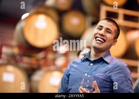 Portrait du jeune homme adulte souriant et tenant un verre de vin rouge. Banque D'Images