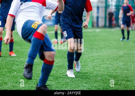 Les garçons de sport blanc et bleu jouent au football sur le terrain, dribbles ball. Jeunes joueurs de football avec balle sur l'herbe verte. Entraînement, football l Banque D'Images