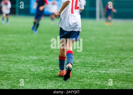 Les garçons de sport blanc et bleu jouent au football sur le terrain, dribbles ball. Jeunes joueurs de football avec balle sur l'herbe verte. Entraînement, football l Banque D'Images