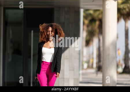 Portrait d'une belle femme afro-américaine debout dans la rue en une journée ensoleillée Banque D'Images