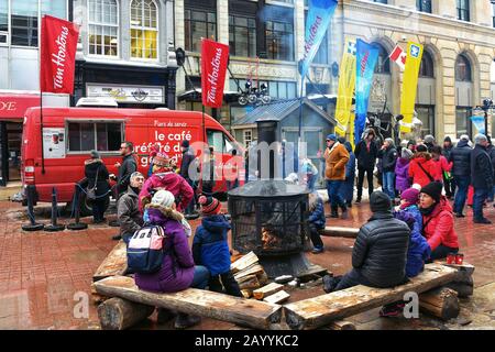 Ottawa, Canada - le 16 février 2020 : les gens sont assis près de la cheminée à bois prévue pour le festival Winterlude près d’une fourgonnette de Tim Horton sur la rue Sparks. Banque D'Images