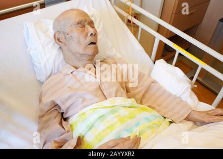 Patient japonais âgé allongé dans le lit dormant à l'hôpital Banque D'Images