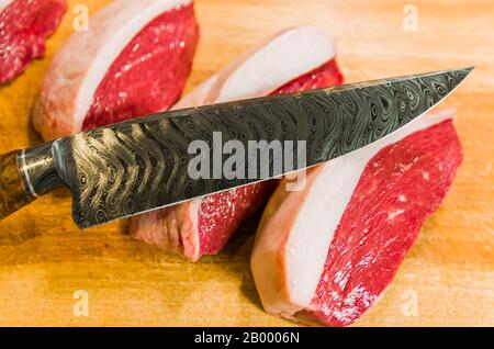 Belle photo de Picanha (top sirloin CAP) coupe sur une planche à découper en bois et un magnifique couteau en acier damassé personnalisé avec le motif brise arkasas. Banque D'Images