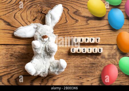 Lapin farci avec message 'Hapy Easter' et de nombreux œufs sur fond en bois Banque D'Images