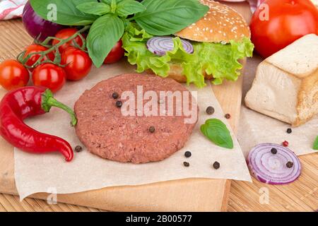 Hamburger et légumes crus à base de légumes sur une planche prête à la cuisson Banque D'Images