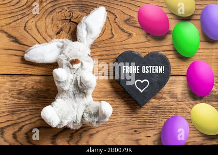 Lapin farci avec message 'Hapy Easter' en allemand sur fond de bois Banque D'Images