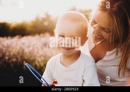 La photo d'un petit garçon caucasien tenu par sa mère est joyeusement et souriant de chaque touche de mère Banque D'Images