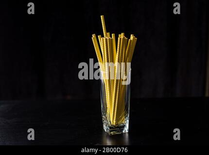 Beaucoup de tubes jaunes dans un verre sur fond noir. Boissons Banque D'Images