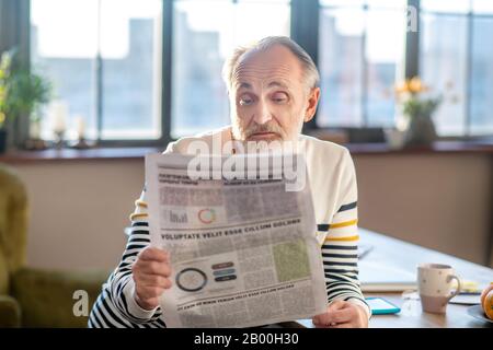 Homme barbu à poil gris dans un pull rayé qui a l'air surpris Banque D'Images