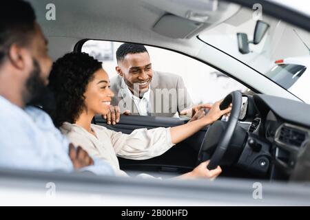 Couple D'Achat De Voiture De Test Avec Le Concessionnaire Assis En Auto Banque D'Images