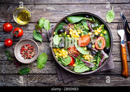 Salade saine, feuilles mélanger salade avec mangold, épinards et légumes dans la plaque sur fond en bois, vue de dessus. Contexte alimentaire. Banque D'Images