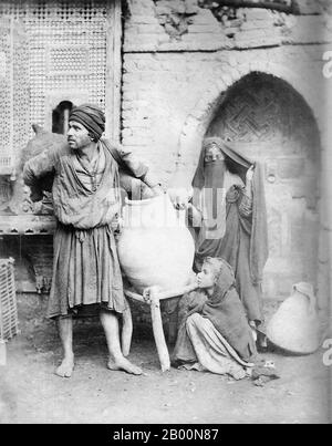 Algérie : Portrait d'un porte-eau et de sa famille, Kasbah, Alger, fin du XIXe siècle. La Casbah (Al Qasbah, la Citadelle), quartier d'Alger est fondée sur les ruines du vieux Icosium. C'est une petite ville qui, construite sur une colline, descend vers la mer, divisée entre la haute ville et la Basse ville. Il y a des maisons et des mosquées datant du XVIIe siècle, ainsi que des labyrinthes de ruelles et de maisons qui sont à la fois pittoresques et déroutantes pour l'extérieur. Banque D'Images