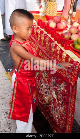 Thaïlande: Un très jeune dévot dans une transe à un autel de rue, Festival végétarien de Phuket. Le Festival végétarien est un festival religieux qui se tient chaque année sur l'île de Phuket dans le sud de la Thaïlande. Il attire des foules de spectateurs en raison de nombreux rituels religieux inhabituels qui sont exécutés. Beaucoup de dévotés religieux se slaleront avec des épées, perce leurs joues avec des objets pointus et commettent d'autres actes douloureux. Banque D'Images