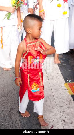 Thaïlande: Un très jeune dévot dans une transe à un autel de rue, Festival végétarien de Phuket. Le Festival végétarien est un festival religieux qui se tient chaque année sur l'île de Phuket dans le sud de la Thaïlande. Il attire des foules de spectateurs en raison de nombreux rituels religieux inhabituels qui sont exécutés. Beaucoup de dévotés religieux se slaleront avec des épées, perce leurs joues avec des objets pointus et commettent d'autres actes douloureux. Banque D'Images