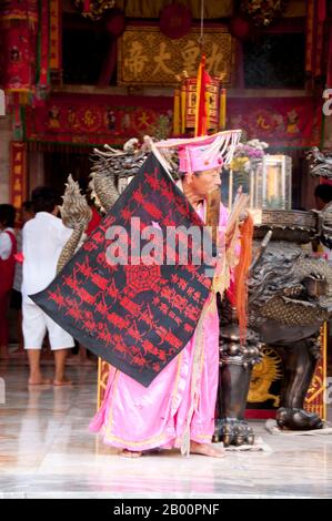 Thaïlande: Une femme âgée 'ma Song' (dévot-entrée) à San Chao Chui Tui (temple taoïste chinois) à la fin du défilé de rue, Festival végétarien de Phuket. Le Festival végétarien est un festival religieux qui se tient chaque année sur l'île de Phuket dans le sud de la Thaïlande. Il attire des foules de spectateurs en raison de nombreux rituels religieux inhabituels qui sont exécutés. Beaucoup de dévotés religieux se slaleront avec des épées, perce leurs joues avec des objets pointus et commettent d'autres actes douloureux. Banque D'Images