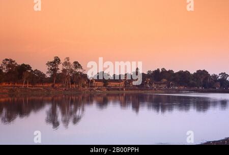 Cambodge: L'entrée et le fossé entourant Angkor Wat pendant que le soleil se couche. Angkor Wat a été construit pour le roi Suryavarman II (gouverné 1113-50) au début du XIIe siècle comme son temple d'état et capitale. En tant que temple le mieux préservé du site d'Angkor, il est le seul à être resté un important centre religieux depuis sa fondation – d'abord hindou, dédié au dieu Vishnu, puis bouddhiste. C'est le plus grand bâtiment religieux au monde. Le temple est au sommet du style classique élevé de l'architecture khmère. Il est devenu un symbole majeur du Cambodge, apparaissant sur son drapeau national. Banque D'Images