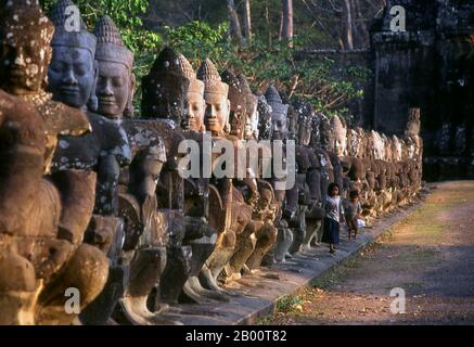 Cambodge: Les enfants à côté du devas (divinités bienveillantes ou anges) qui bordent la route de la porte Sud, Angkor Thom. Les Devas sont souvent vus en opposition à Asura (déités pécheresses). Angkor Thom est situé à 1,5 km au nord d'Angkor Wat. Il a été construit à la fin du XIIe siècle par le roi Jayavarman VII, et couvre une superficie de 9 km², à l'intérieur desquels sont situés plusieurs monuments des époques antérieures ainsi que ceux établis par Jayavarman et ses successeurs. On croit qu'il a soutenu une population de 80,000 à 150,000 personnes. Au centre de la ville se trouve le temple d'état de Jayavarman, le Bayon. Banque D'Images