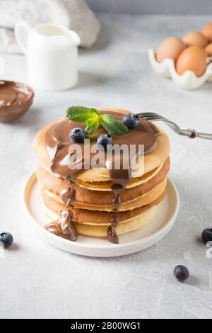 Une pile de crêpes maison et douce avec du chocolat et du bleuet sur une table légère. Gros plan. Banque D'Images