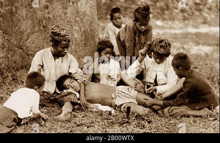 Birmanie/Myanmar: Un garçon est tatoué à Mong Lim dans l'État de Shan, 1890. Le groupe ethnique Shan a popularisé l'art du tatouage en Birmanie, en important la pratique en provenance du sud de la Chine. Leurs tatouages avaient des connotations magiques ou spirituelles, semblables à la croyance en des amulettes. Dans la culture Shan, un jeune homme était souvent tatoué de la taille aux genoux comme un rite de passage et était un signe de virilité et de maturité. Le rituel a été exécuté par l'homme de médecine du village, en utilisant une longue brochette pour appliquer l'encre indigo traditionnelle ou vermillon naturel. La procédure peut prendre des semaines et le sujet sera drogué. Banque D'Images