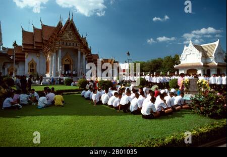 Thaïlande: Des écoliers attendent le roi de Thaïlande, Bhumibol Adulyadej, à Wat Benchamabophit, Bangkok. Le nom complet du temple est Wat Benchamabophit Dusitvanaram. Il est également connu sous le nom de temple de marbre. La construction du temple a commencé en 1899 à la demande du roi Chulalongkorn après la construction de son palais à proximité. Le nom du temple signifie littéralement le temple du cinquième roi situé à proximité du palais Dusit. Il a été conçu par le prince Naris, demi-frère du roi, et est construit en marbre italien. Banque D'Images