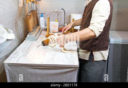 Préparation du traditionnel Trdelnik une sorte de gâteau de broche fait de pâte roulée enveloppée autour d'un bâton, grillé. Banque D'Images