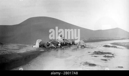 Chine : les hommes de Sir Aurel Stein buvant sur la rivière Keriya après une traversée dangereuse du désert de Taklamakan, 1908.Le Taklamakan est l'un des plus grands déserts sablonneux du monde, avec une taille de 18th dans le classement des plus grands déserts non polaires du monde.Elle couvre une superficie de 270 000 km2 (100 000 mi carrés) du bassin de Tarim, 1 000 kilomètres (620 mi) de long et 400 kilomètres (250 mi) de large.Il est traversé à sa limite nord et à sa limite sud par deux branches de la route de la soie tandis que les voyageurs cherchaient à éviter les terres arides. Banque D'Images