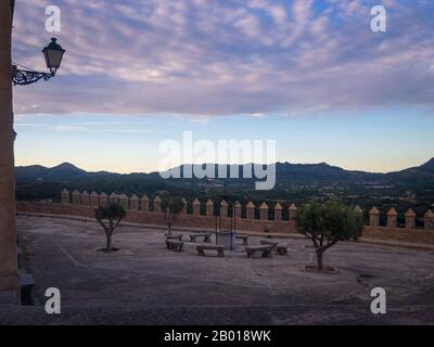 Cloître avec bancs et bien dans le Sanctuaire de Sant Salvador Arta, Majorque (Majorque) sur les montagnes d'arrière-plan et les nuages après le coucher du soleil Banque D'Images