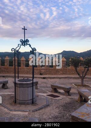 Cloître avec bancs et bien dans le Sanctuaire de Sant Salvador Arta, Majorque (Majorque) sur les montagnes d'arrière-plan et les nuages après le coucher du soleil Banque D'Images