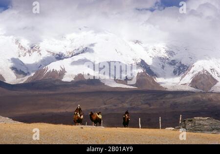 Chine: Chameaux de Bactrian et riders de Kirghiz près du lac Karakul sur l'autoroute de Karakoram, Xinjiang. Deux petites colonies de nomades Kirghiz (Kirgiz ou Kirgiz) se trouvent sur le côté du lac Karakul, dans les montagnes du Pamir. Les visiteurs peuvent passer la nuit dans l'une de leurs mobile homes ou yourtes. Les hommes de Kirghiz s'approchent des voyageurs à leur arrivée au lac et proposent d'organiser cet hébergement. Les Kirghizistan forment l'un des 56 groupes ethniques officiellement reconnus par la République populaire de Chine. Il y a plus de 145 000 000 Kirghizes en Chine. Banque D'Images