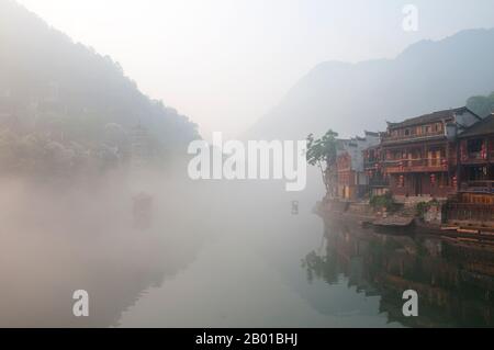 Chine : tôt le matin sur la rivière Túo brumisty de Fenghuang, Fenghuang, province de Hunan. Fenghuang est chinois pour Phoenix et se réfère à la mythique oiseau de feu sacré qui peut être trouvé dans les mythologies des Perses, Grecs, Romains, Egyptiens, Chinois, Et (selon Sanchuniathon) les Phéniciens. La légende suggère que deux phénolxes à la découverte de la ville ont survolé pendant un certain temps avant de voler à contrecœur. La ville de Fenghuang est une ancienne ville bien conservée qui remonte à 248 av. J.-C. Elle abrite les minorités Miao et Tujia. Banque D'Images