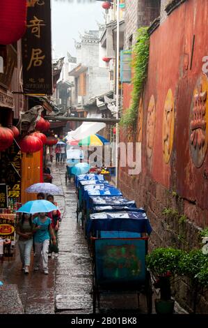 Chine: Des rickshaws alignés sur l'une des vieilles rues tortueuses de Fenghuang, province de Hunan. Fenghuang est chinois pour Phoenix et se réfère à la mythique oiseau de feu sacré qui peut être trouvé dans les mythologies des Perses, Grecs, Romains, Egyptiens, Chinois, Et (selon Sanchuniathon) les Phéniciens. La légende suggère que deux phénolxes à la découverte de la ville ont survolé pendant un certain temps avant de voler à contrecœur. La ville de Fenghuang est une ancienne ville bien conservée qui remonte à 248 av. J.-C. Elle abrite les minorités Miao et Tujia. Banque D'Images