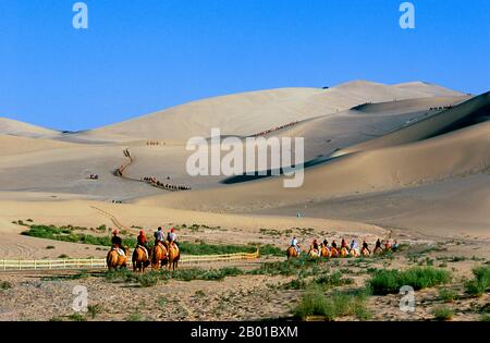 Chine : touristes chinois sur les dunes de sable chantant de Mingsha Shan (collines de Mingsha) dans le désert de Kumtagh, province de Gansu. Mingsha Shan (Singing Sand Dunes) sont situés à environ 4km au sud de Dunhuang. Ce sont les dunes de sable les plus grandes et les plus impressionnantes de Chine. Les dunes principales s'élèvent entre 250m et 300m. Ils sont appelés ‘Sablest’ parce que les grains de sable qui se déplacent font un bourdonnement dans les vents puissants. Le désert de Kumtagh est une section du désert de Taklamakan qui se trouve à l'est et au sud-est du désert de lop. Banque D'Images