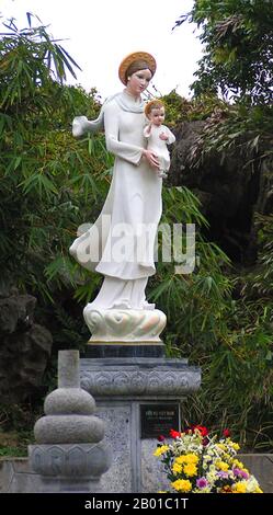 Vietnam: Notre Dame de Phat Diem Cathédrale - la Vierge Marie, vêtue d'une robe vietnamienne ao dai, porte le bébé Jésus. Photo par Tango7174 (Licence CC BY-sa 4,0). L'ao dai (vietnamien: Áo dài) est un costume national vietnamien, aujourd'hui le plus souvent pour les femmes. Dans sa forme actuelle, il s'agit d'une tunique en soie ajustée sur des pantaluons. Le mot est prononcé OW-Zye au nord et OW-yai au sud, et se traduit par «robe longue». Le nom áo dài a été appliqué à l'origine à la robe portée à la cour des seigneurs de Nguyễn à Huế au 18th siècle. Cette tenue a évolué en l'áo ngũ thân. Banque D'Images