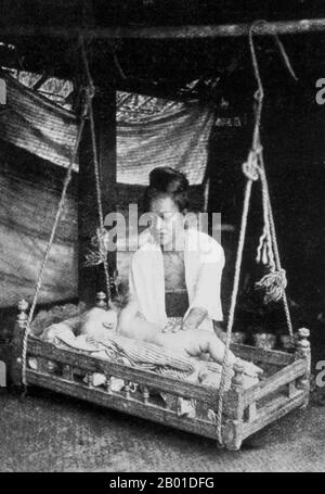 Birmanie: Une mère birmane s'occupe de son enfant qui se trouve dans un berceau en bois balançoire (birman: 'Sunngban'), vers 1892-1896. La conquête britannique de la Birmanie a commencé en 1824 en réponse à une tentative birmane d'envahir l'Inde. En 1886, et après deux autres guerres, la Grande-Bretagne avait incorporé tout le pays dans le Raj britannique. Pour stimuler le commerce et faciliter les changements, les Britanniques ont fait venir des Indiens et des Chinois, qui ont rapidement déplacé les Birmans dans les zones urbaines. À ce jour, Rangoon et Mandalay ont de grandes populations indiennes ethniques. Des chemins de fer et des écoles ont été construits, ainsi qu'un grand nombre de prisons. Banque D'Images