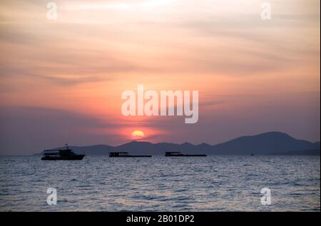 Thaïlande: Vue vers Ko Larn au coucher du soleil de Pattaya, province de Chonburi. Ko Larn se trouve à 7 km (4,5 miles) de la côte de Pattaya et est à seulement 4km de long et 2 km de large. Le port principal est Naban Pier. Il y a six plages sur l'île, toutes des petites criques pittoresques qui se connectent à l'embarcadère de Naban par une route en béton. Vous pourrez vous déplacer dans l'île en prenant un taxi pour les camions, un taxi pour les motos ou en louant des motos. Chaque plage dispose de maisons d'hôtes, de restaurants, de boutiques et d'installations touristiques. En haute saison ou le week-end, l'île est très populaire. Banque D'Images