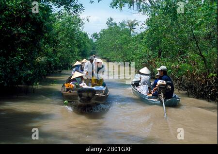 Vietnam : transport dans les voies navigables du delta du Mékong. Le sud du Vietnam est dominé par les riches terres agricoles du delta du Mékong, principale source de production de riz, de fruits et légumes du pays. La terre est alluviale et de faible altitude, avec des marais et des forêts de mangroves à l'ouest et au sud. Pendant la saison des pluies, l'eau couvre un tiers du delta, avec des inondations allant jusqu'à 13 pieds (4 m). Par endroits, l'eau salée empiète sur le delta jusqu'à 30 m (48 km). Bien que extraordinairement fertiles, certaines parties du delta doivent encore être cultivées. Banque D'Images